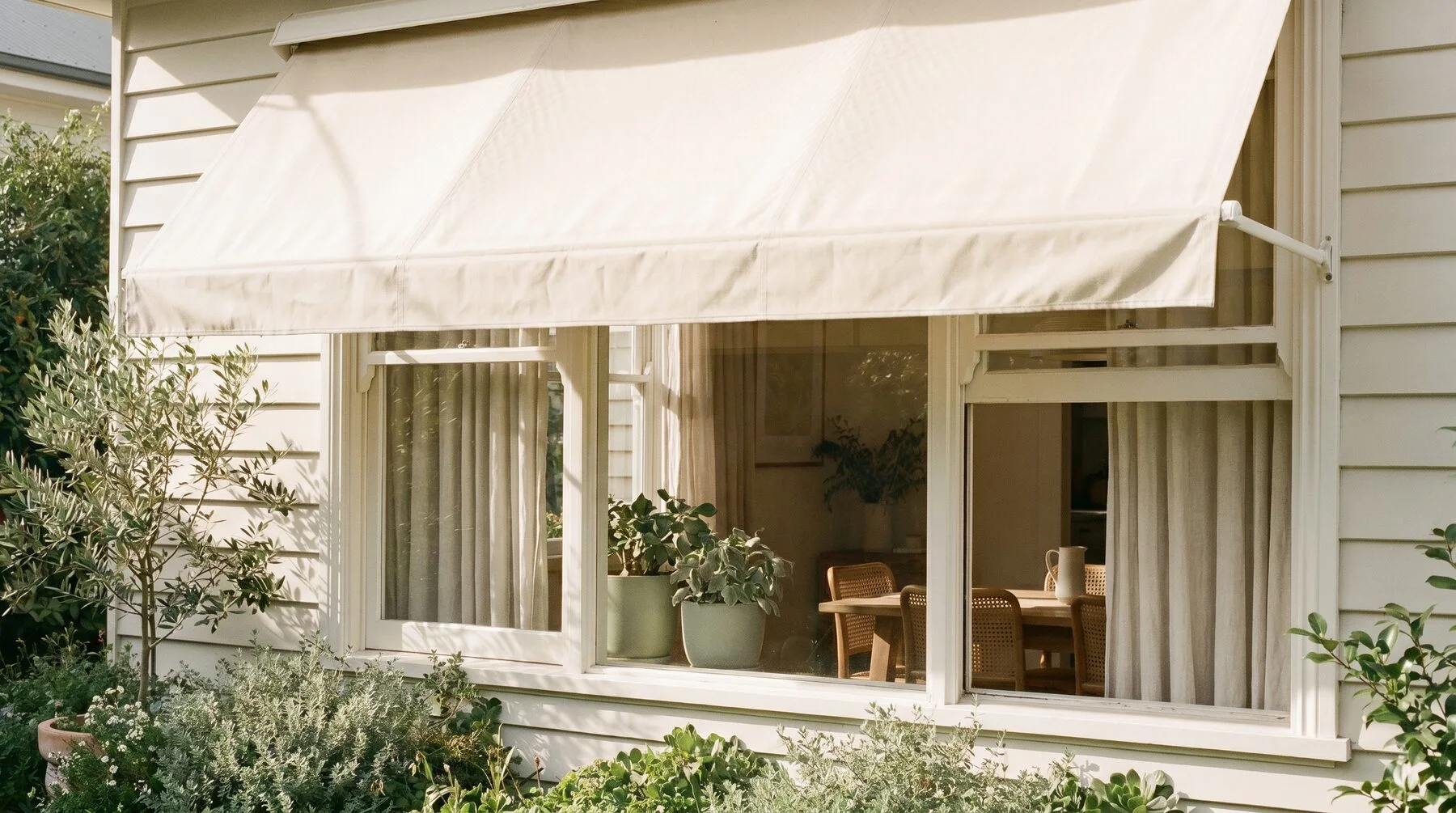 A cream canvas awning shading a weatherboard home's window