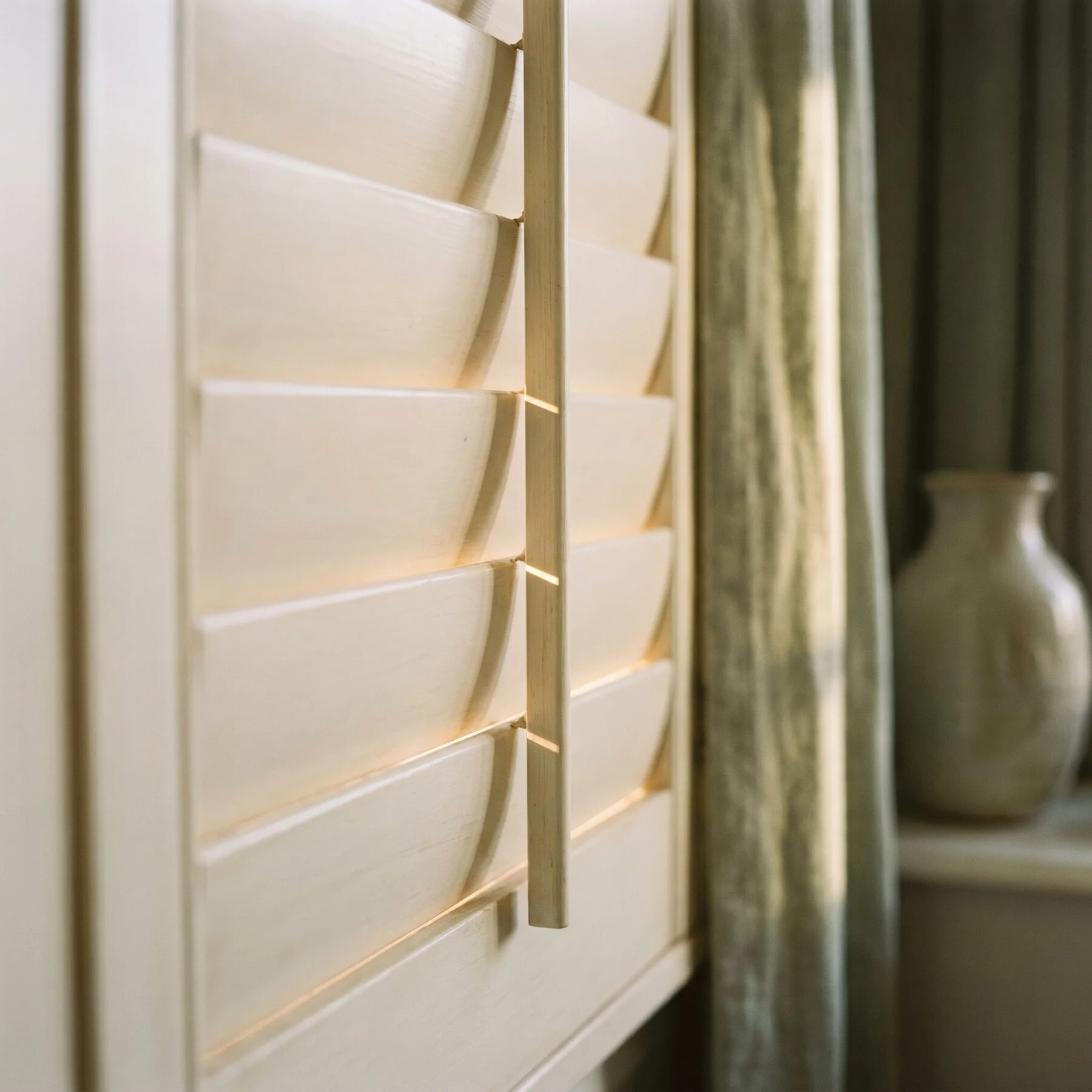 Morning light escaping between two nearly-closed shutter louvres